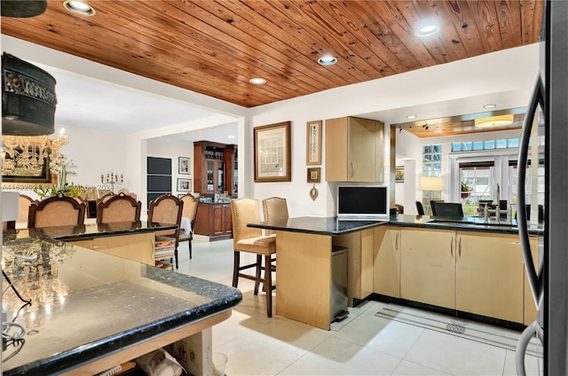 kitchen featuring dark stone countertops, wood ceiling, kitchen peninsula, and a breakfast bar area