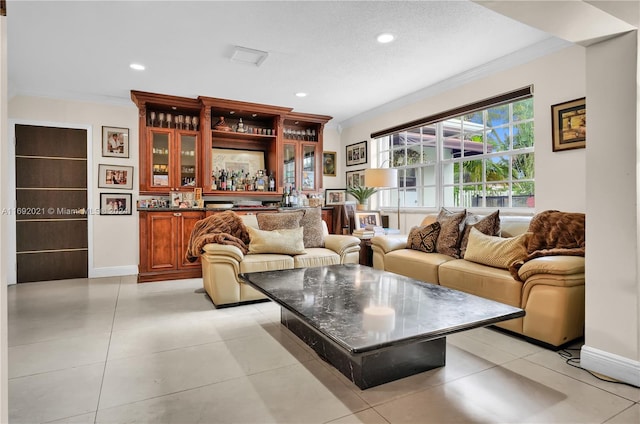 living room with bar area, a textured ceiling, light tile patterned floors, and crown molding