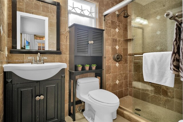 bathroom featuring tile walls, a shower with door, backsplash, vanity, and toilet