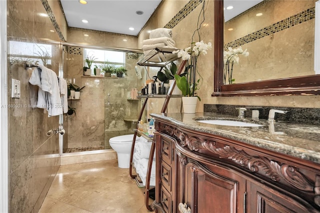 bathroom featuring walk in shower, vanity, toilet, and tile walls