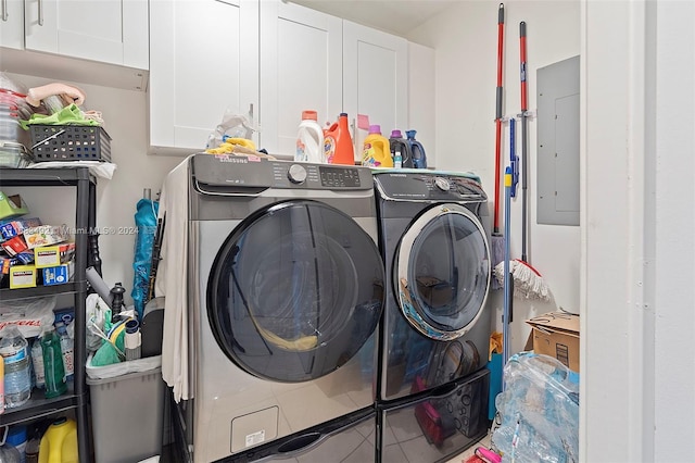 laundry area with electric panel, washing machine and dryer, and cabinets