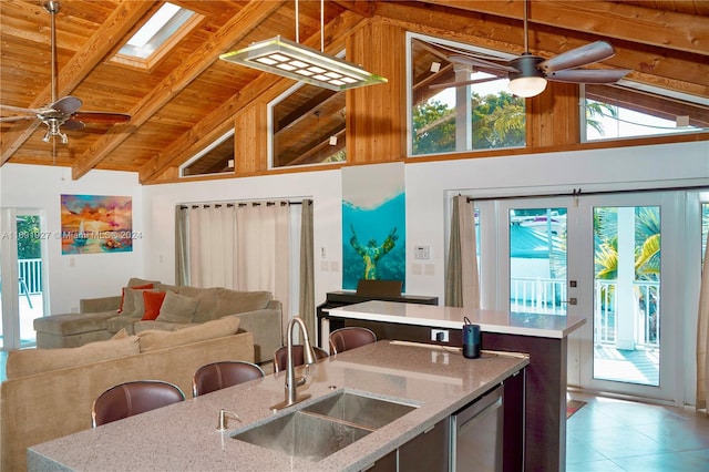 kitchen featuring beam ceiling, high vaulted ceiling, hanging light fixtures, sink, and a skylight