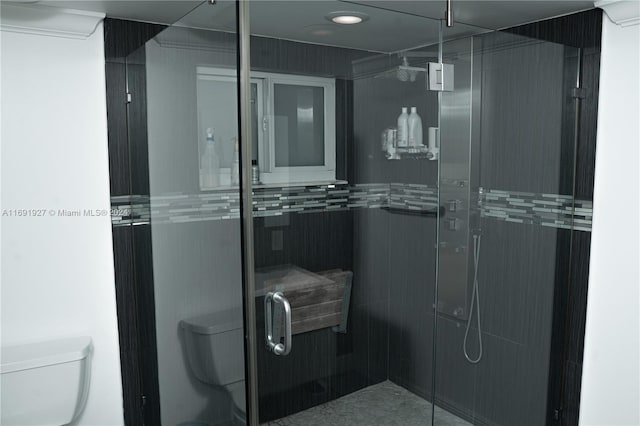 bathroom featuring toilet and a shower with shower door