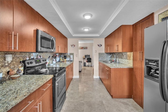 kitchen featuring stainless steel appliances, light stone counters, sink, tasteful backsplash, and a raised ceiling