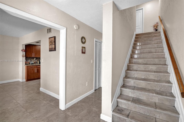 stairway featuring a textured ceiling