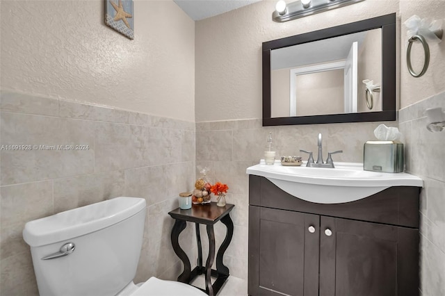 bathroom with tile walls, vanity, and toilet