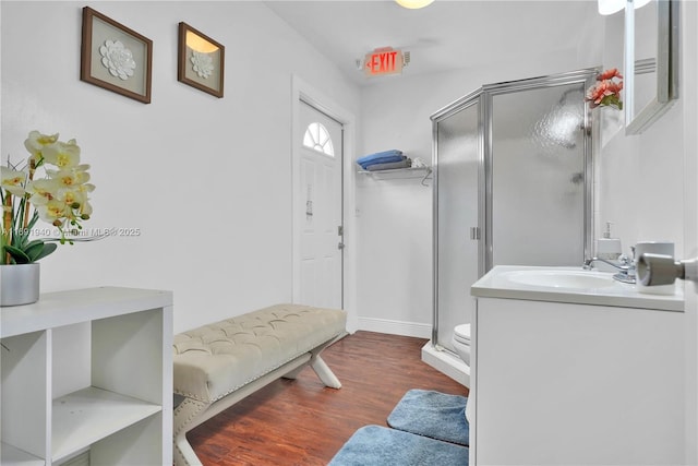 bathroom with hardwood / wood-style flooring, vanity, a shower with door, and toilet