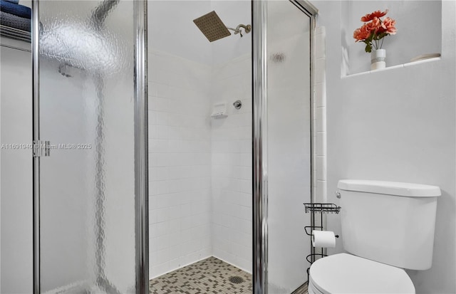 bathroom with a shower with shower door and toilet