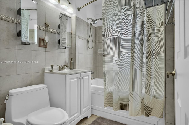 full bathroom featuring vanity, tile patterned floors, toilet, shower / bath combo with shower curtain, and tile walls