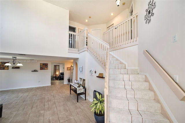 staircase featuring tile patterned flooring and a high ceiling