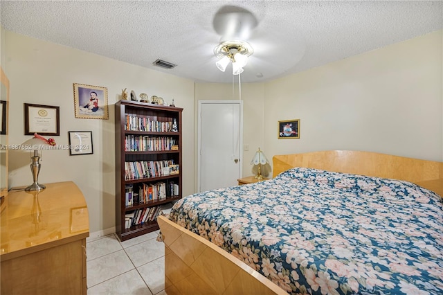 tiled bedroom with ceiling fan and a textured ceiling