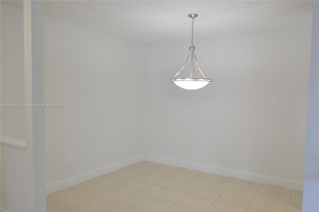 spare room featuring a textured ceiling and light tile patterned floors