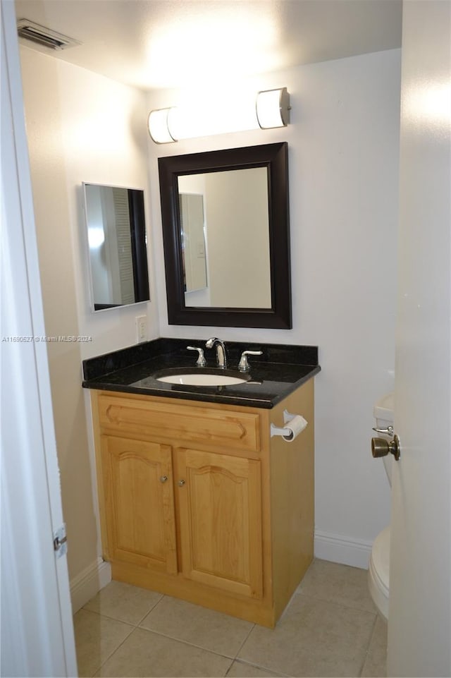 bathroom with toilet, vanity, and tile patterned floors