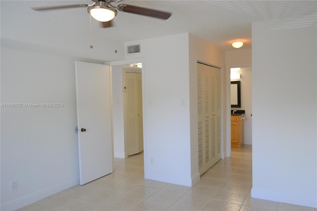 interior space featuring ceiling fan, a textured ceiling, and light tile patterned floors