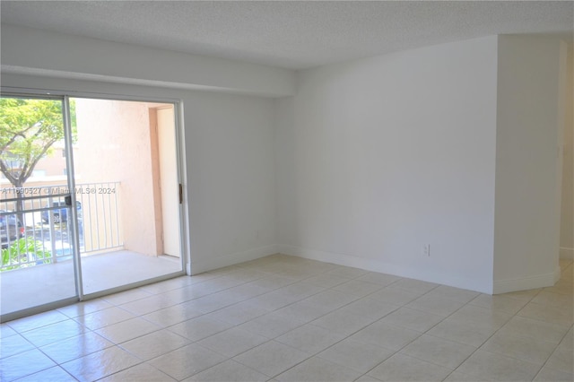 tiled empty room with a textured ceiling