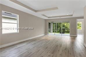 empty room featuring wood-type flooring and a raised ceiling