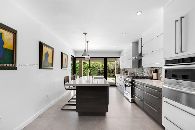 kitchen with a kitchen island, appliances with stainless steel finishes, hanging light fixtures, a kitchen breakfast bar, and white cabinets