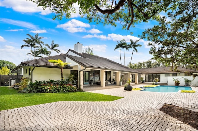 rear view of house featuring a fenced in pool and a patio area