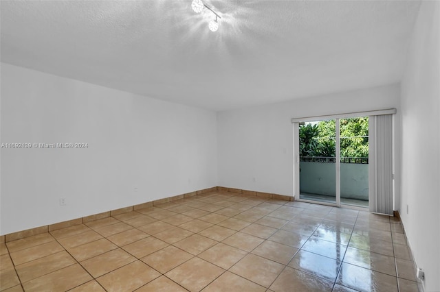 unfurnished room with a textured ceiling and light tile patterned flooring