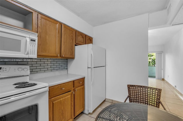 kitchen featuring backsplash, white appliances, a textured ceiling, and light tile patterned floors