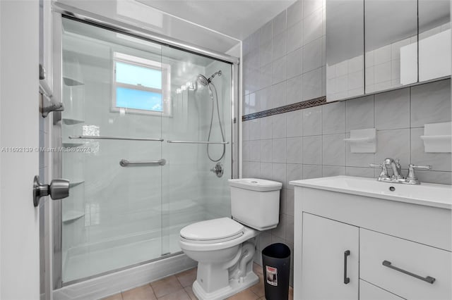 bathroom featuring tile walls, tile patterned floors, vanity, an enclosed shower, and toilet