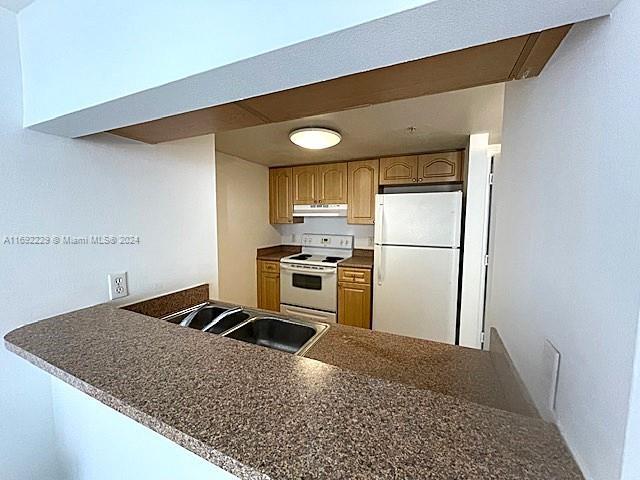 kitchen with kitchen peninsula, white appliances, and sink