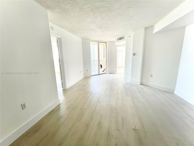 spare room with light hardwood / wood-style floors and a textured ceiling