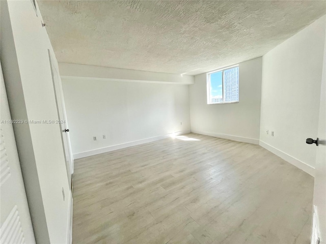 empty room with light hardwood / wood-style floors and a textured ceiling