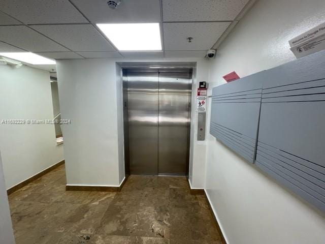 hall featuring a paneled ceiling and elevator