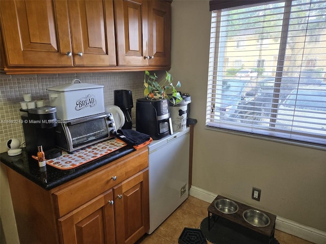 washroom with plenty of natural light, laundry area, baseboards, and light tile patterned floors