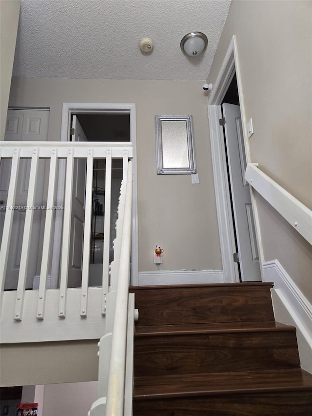 stairway featuring a textured ceiling