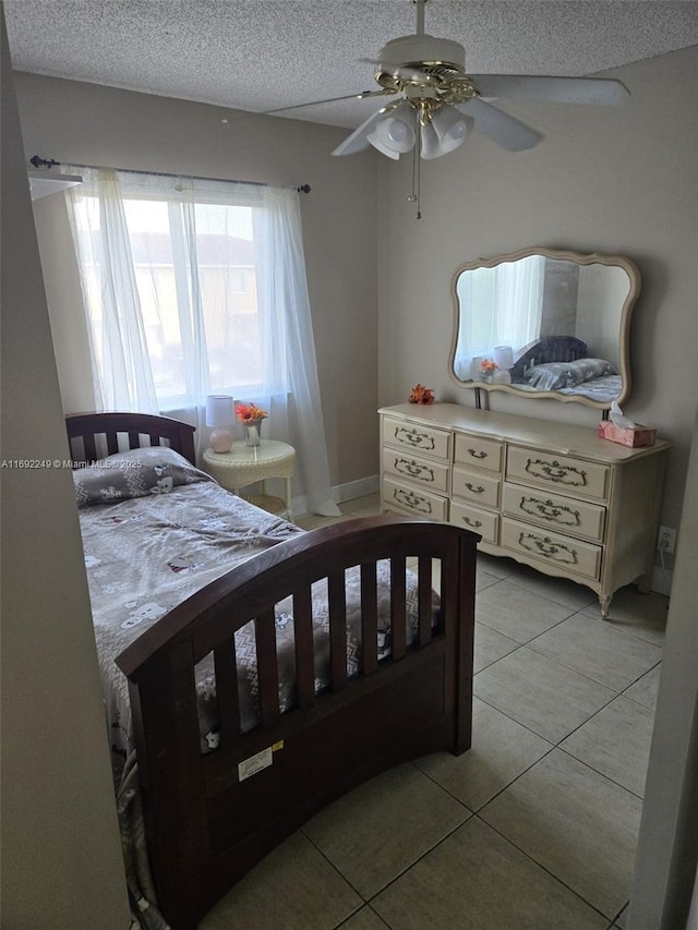 tiled bedroom featuring ceiling fan and a textured ceiling