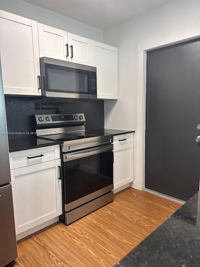 kitchen with appliances with stainless steel finishes, light hardwood / wood-style floors, and white cabinetry