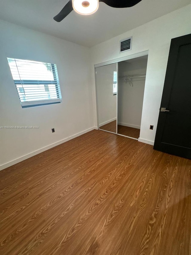 unfurnished bedroom with hardwood / wood-style flooring, ceiling fan, and a closet