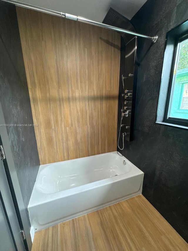 bathroom featuring washtub / shower combination and hardwood / wood-style flooring