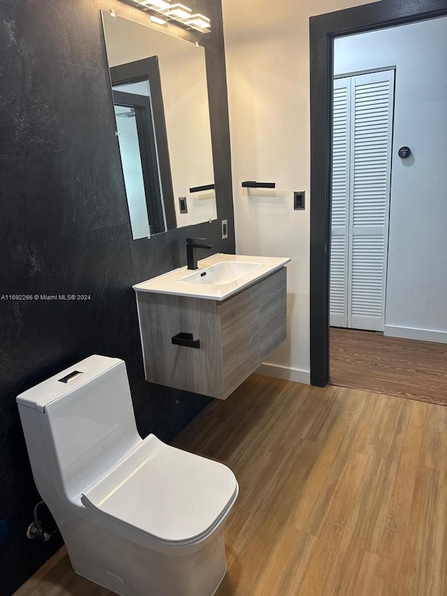 bathroom with wood-type flooring, vanity, and toilet