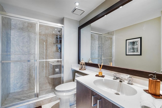 bathroom with an enclosed shower, vanity, and toilet