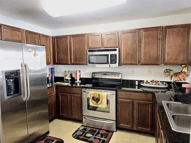 kitchen featuring sink, light tile patterned flooring, a textured ceiling, and appliances with stainless steel finishes