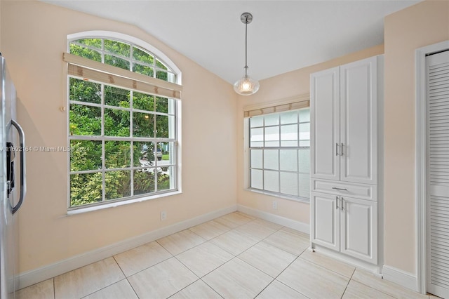 unfurnished dining area featuring vaulted ceiling and light tile patterned floors