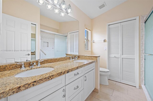 bathroom with vanity, a shower with shower door, tile patterned floors, toilet, and vaulted ceiling