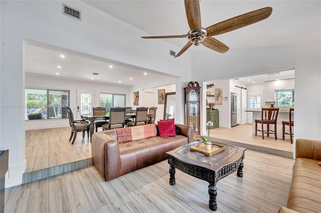 living room featuring light hardwood / wood-style floors, ceiling fan, and lofted ceiling