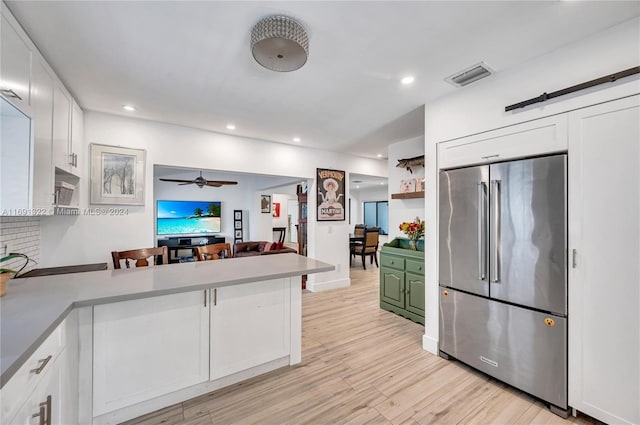 kitchen featuring a breakfast bar, ceiling fan, white cabinets, light hardwood / wood-style floors, and built in fridge