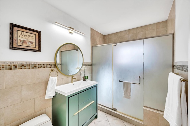 bathroom with toilet, vanity, tile patterned floors, and tile walls