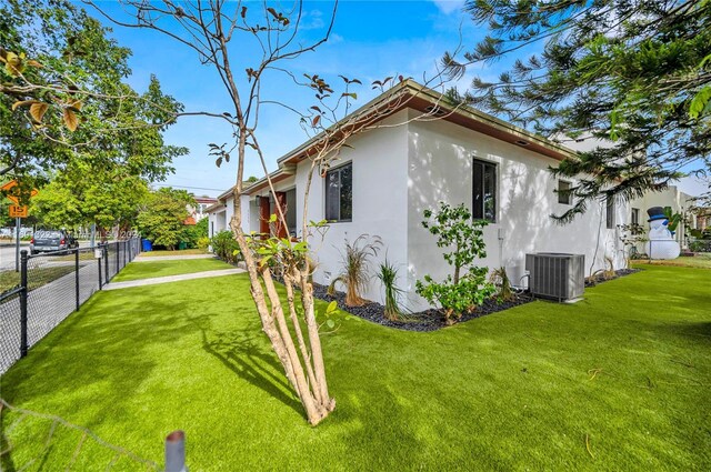 view of side of home featuring central AC unit and a yard