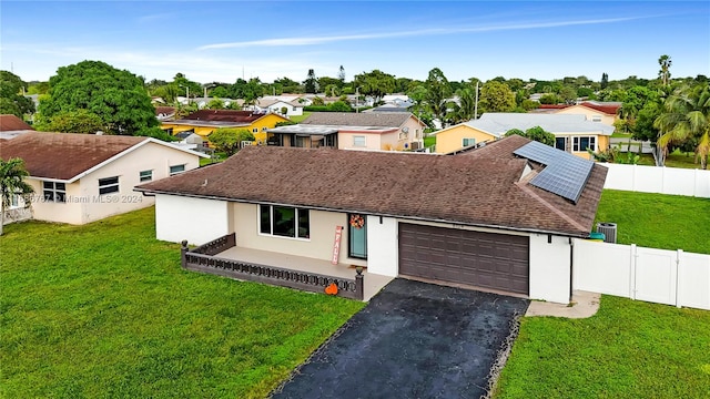 view of front facade featuring a front yard, solar panels, and a garage