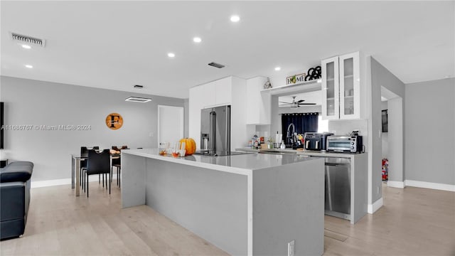 kitchen featuring stainless steel appliances, white cabinets, light wood-type flooring, and a kitchen island