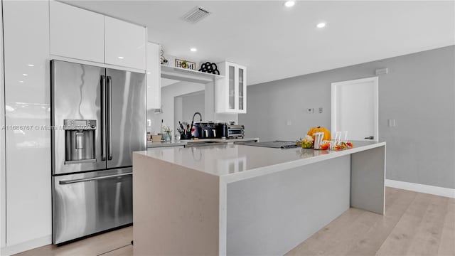 kitchen with stainless steel refrigerator with ice dispenser, white cabinetry, light hardwood / wood-style floors, and a center island