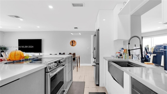 kitchen with stainless steel appliances, white cabinetry, and sink