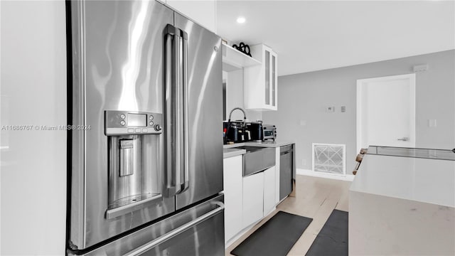 kitchen with white cabinets, sink, light hardwood / wood-style flooring, and appliances with stainless steel finishes