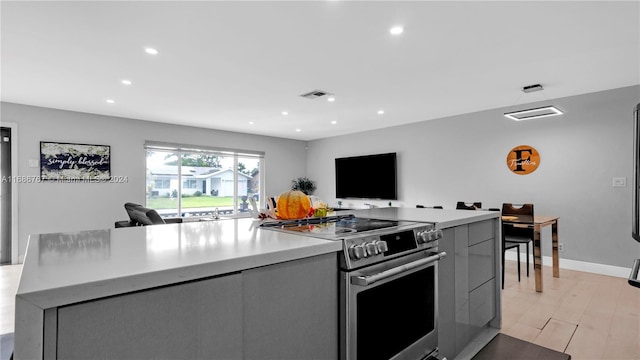 kitchen featuring gray cabinets, light hardwood / wood-style floors, stainless steel range oven, and a kitchen island